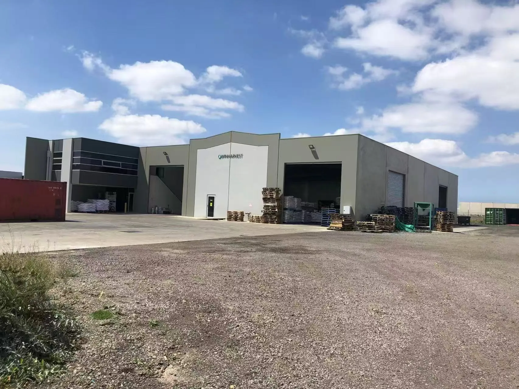 Exterior of a modern WinHarvest warehouse with loading areas and pallets